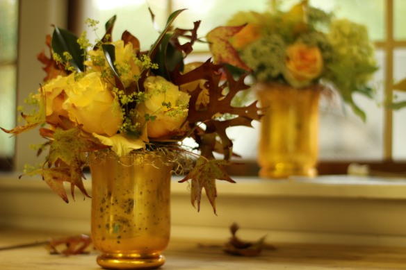 Fall Design using gold hurricane vase with a decorative mesh wire net holding stems in place